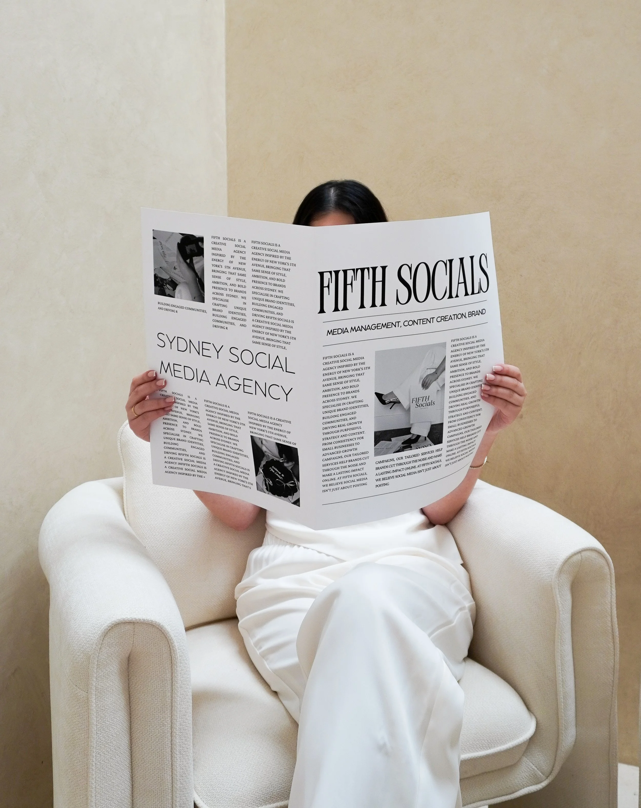 girl sitting on couch with newspaper that says fifth socials a social media management agency