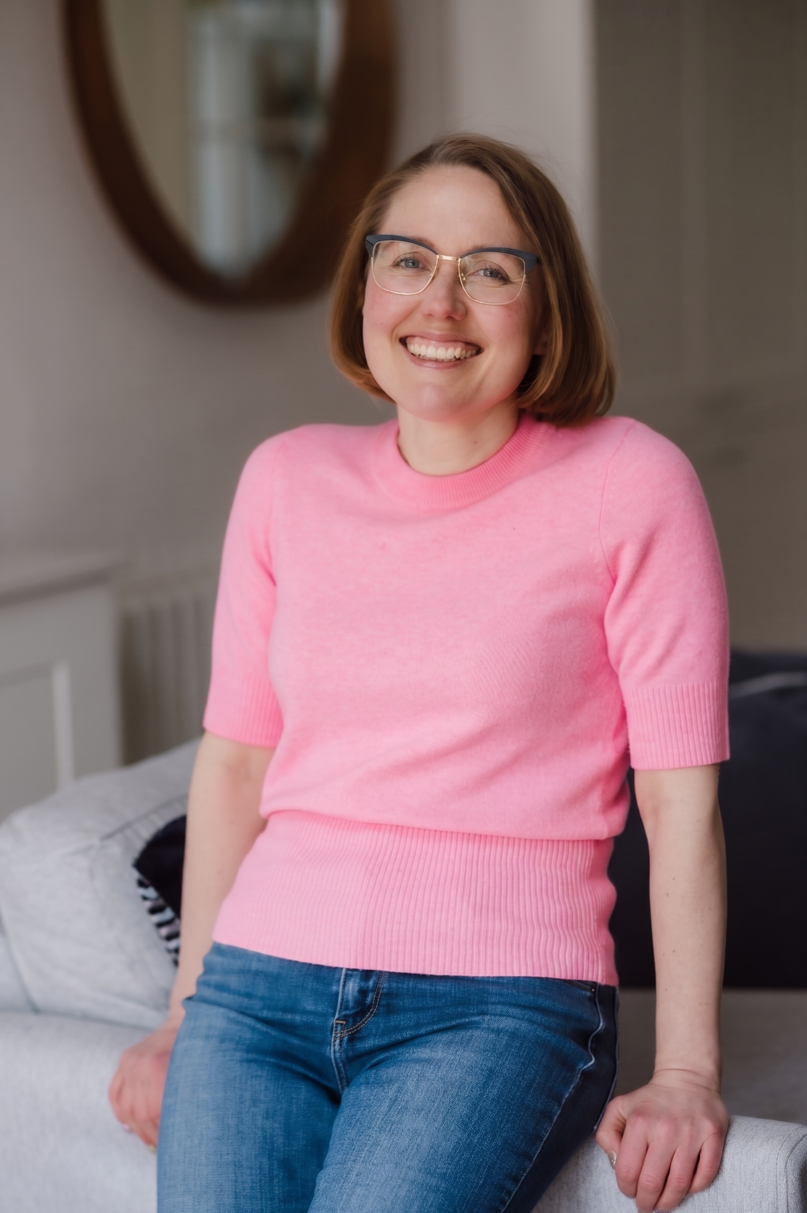 woman standing and leaning against the side of a sofa, smiling