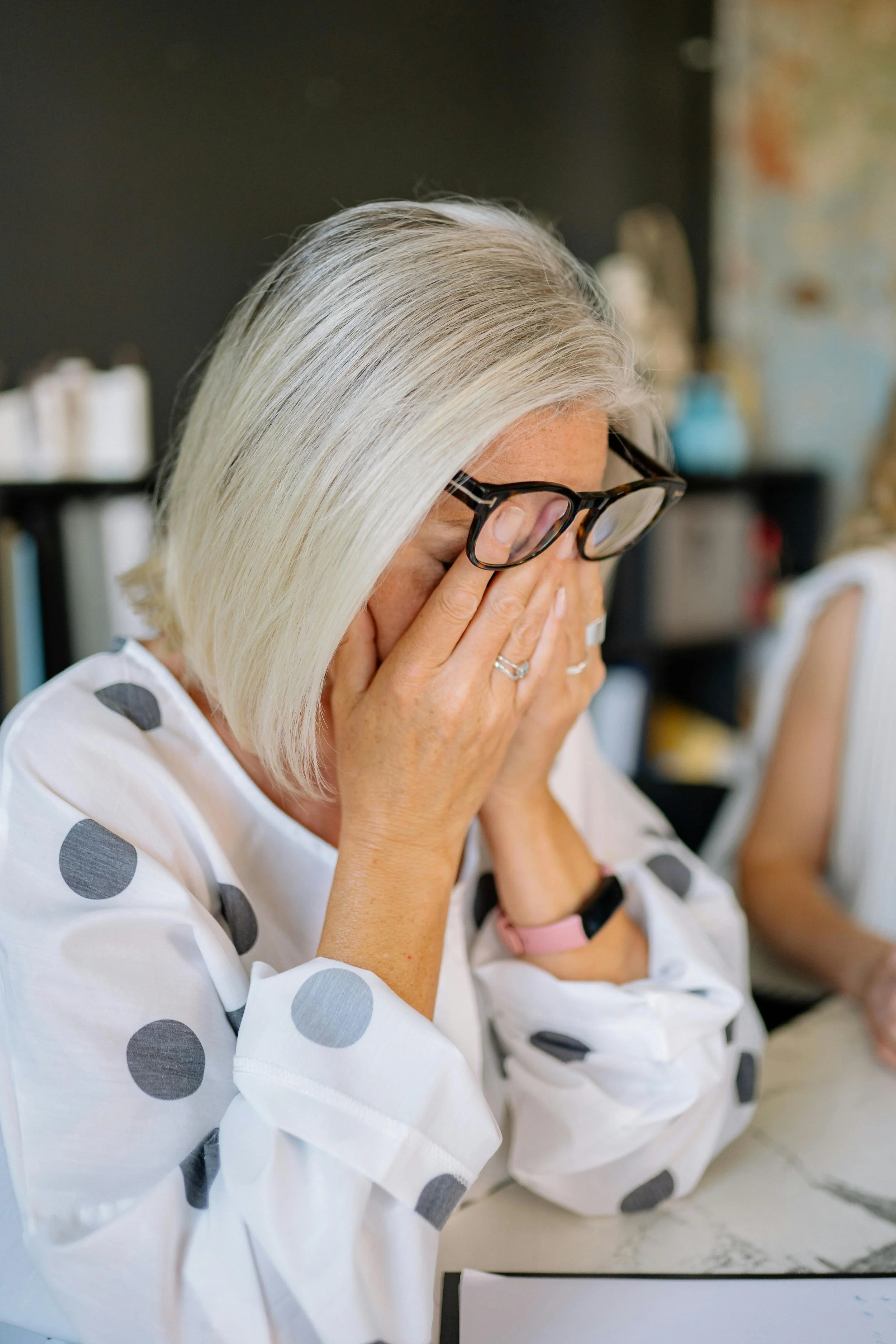 A woman looking exhausted and rubbing her eyes under her glasses