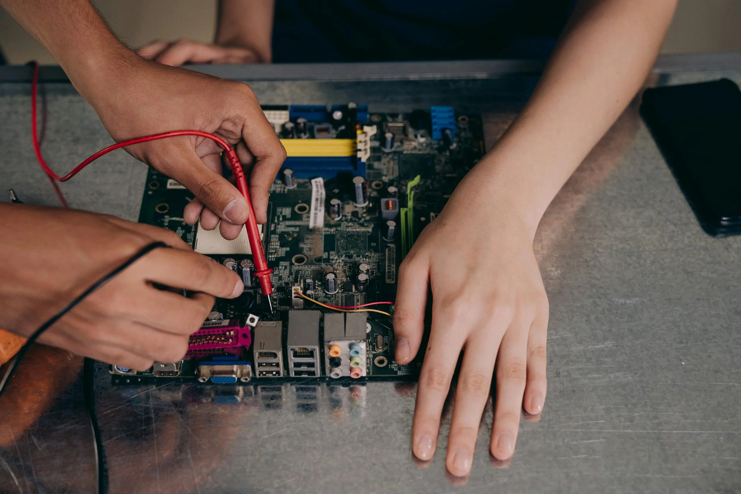 two pair of hands manipulating a circuit board