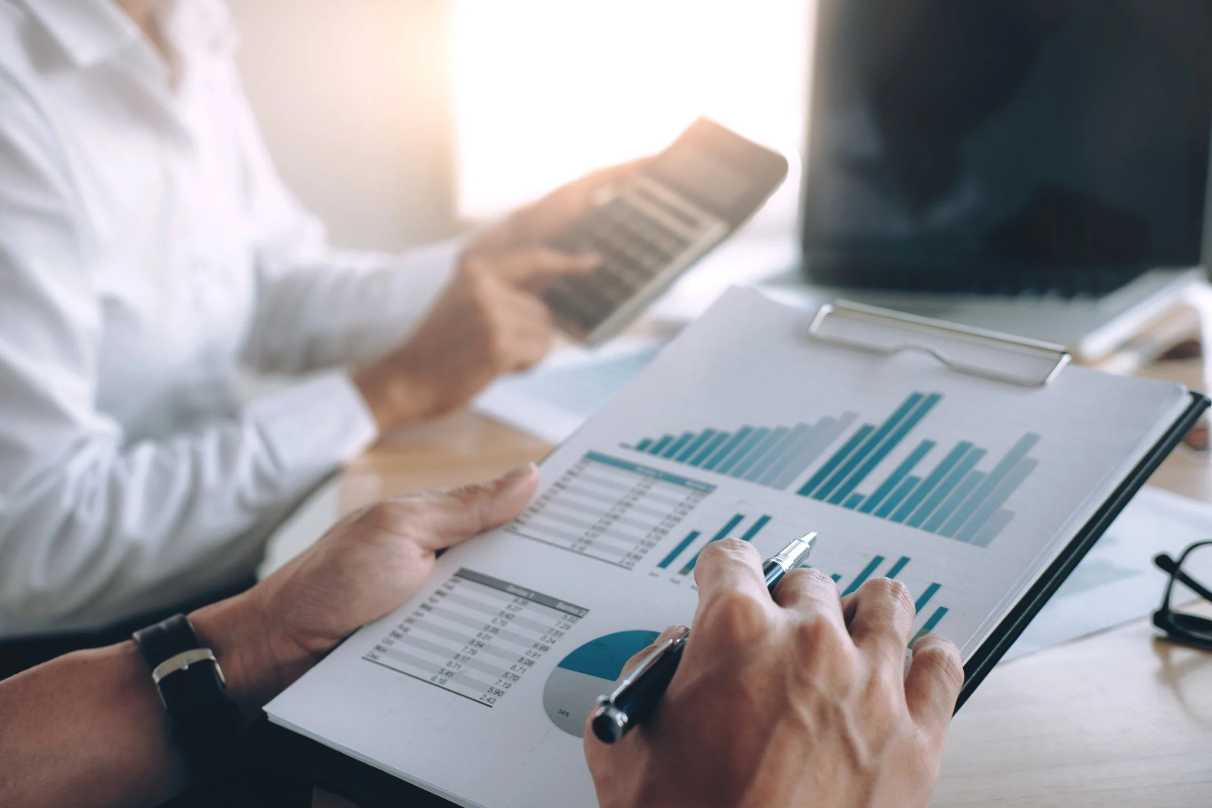 Persona revisando informes financieros con gráficos en una tabla de oficina.