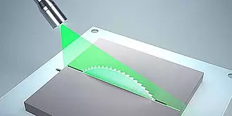A green laser beam scanning a window or mirror with a grid pattern, likely in a laboratory or scientific setting.