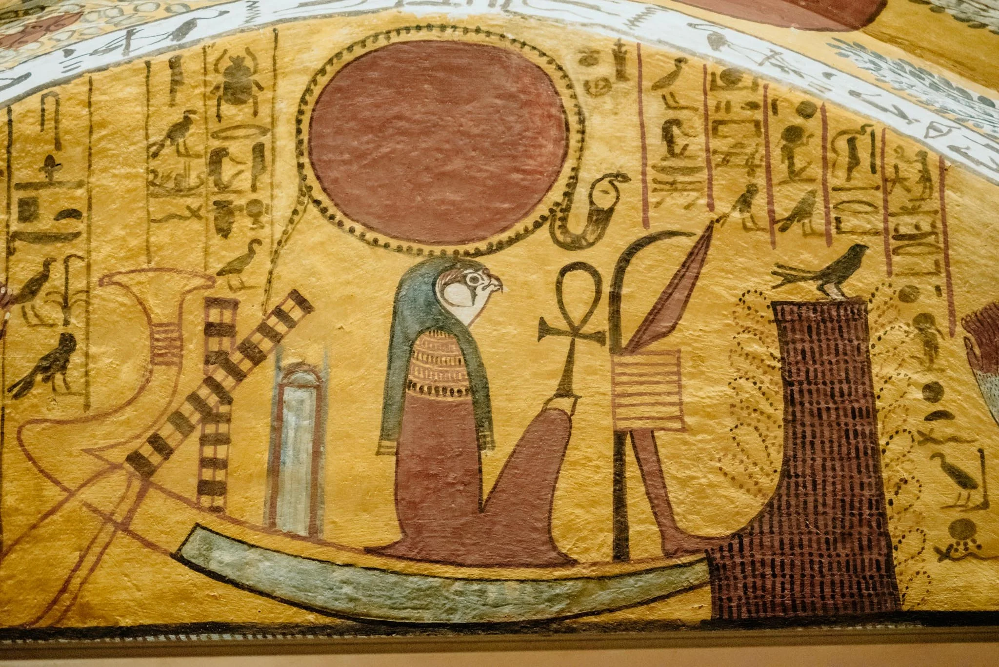 Close-up of ancient Egyptian hieroglyphics and symbolic drawings on a yellow background, in the tomb of the scribes Luxor