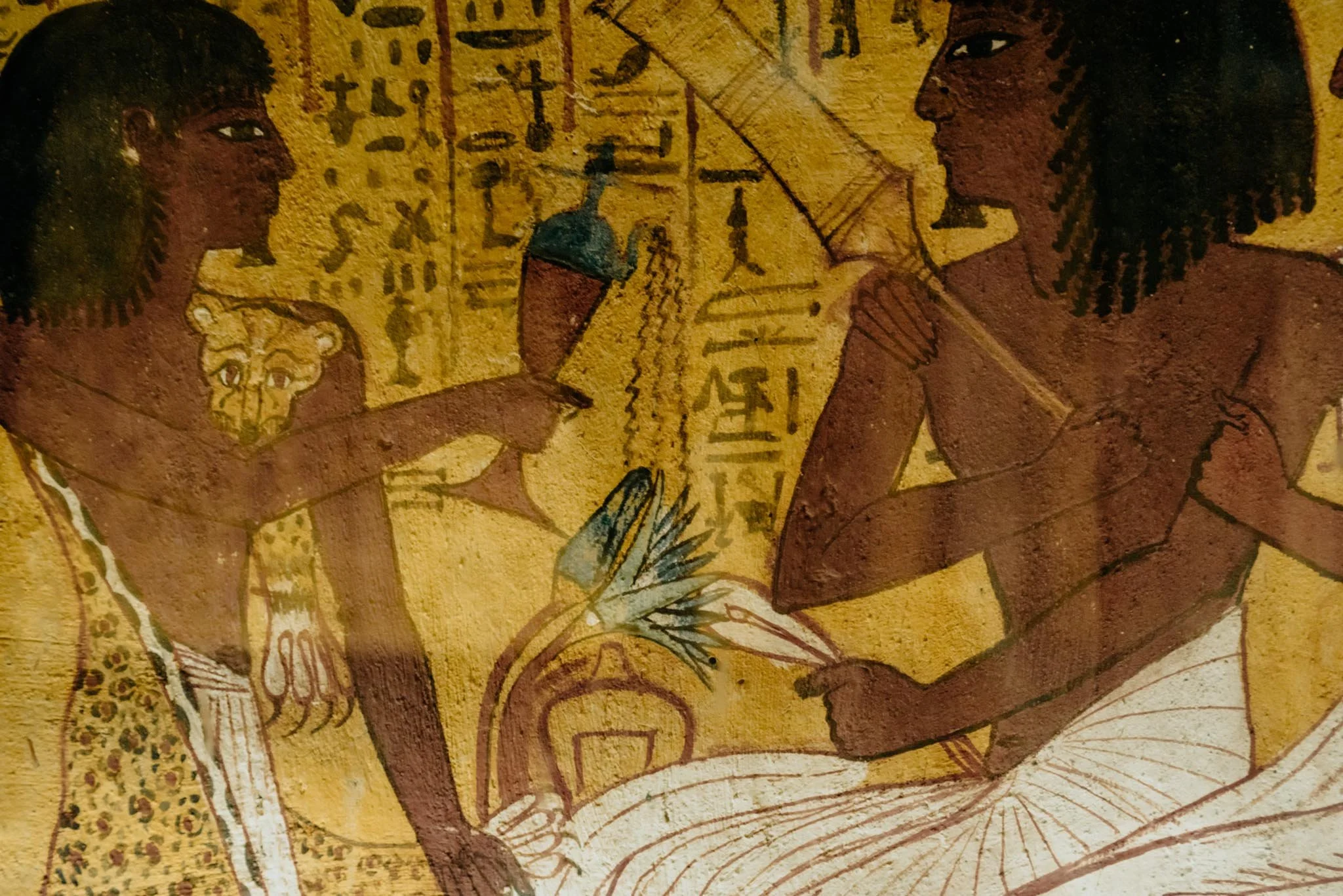 Ancient Egyptian painting of two figures facing each other, with hieroglyphs and symbols in the background.