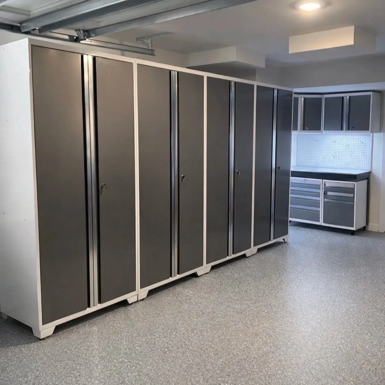 A garage with large gray storage lockers on the left and a workbench with cabinets on the right.