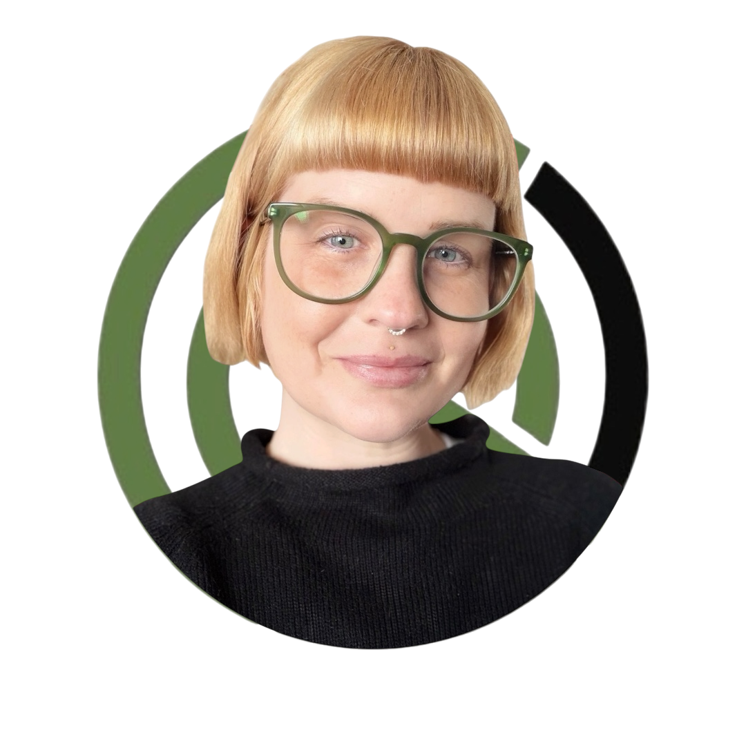 A woman with short blonde hair, large green glasses, and wearing a black top.