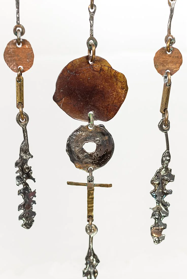 Stainless steel worked into five feathered drops. The colour comes from the flame, not from patina, and the highlights are polished in after, each hung free to turn with the air.