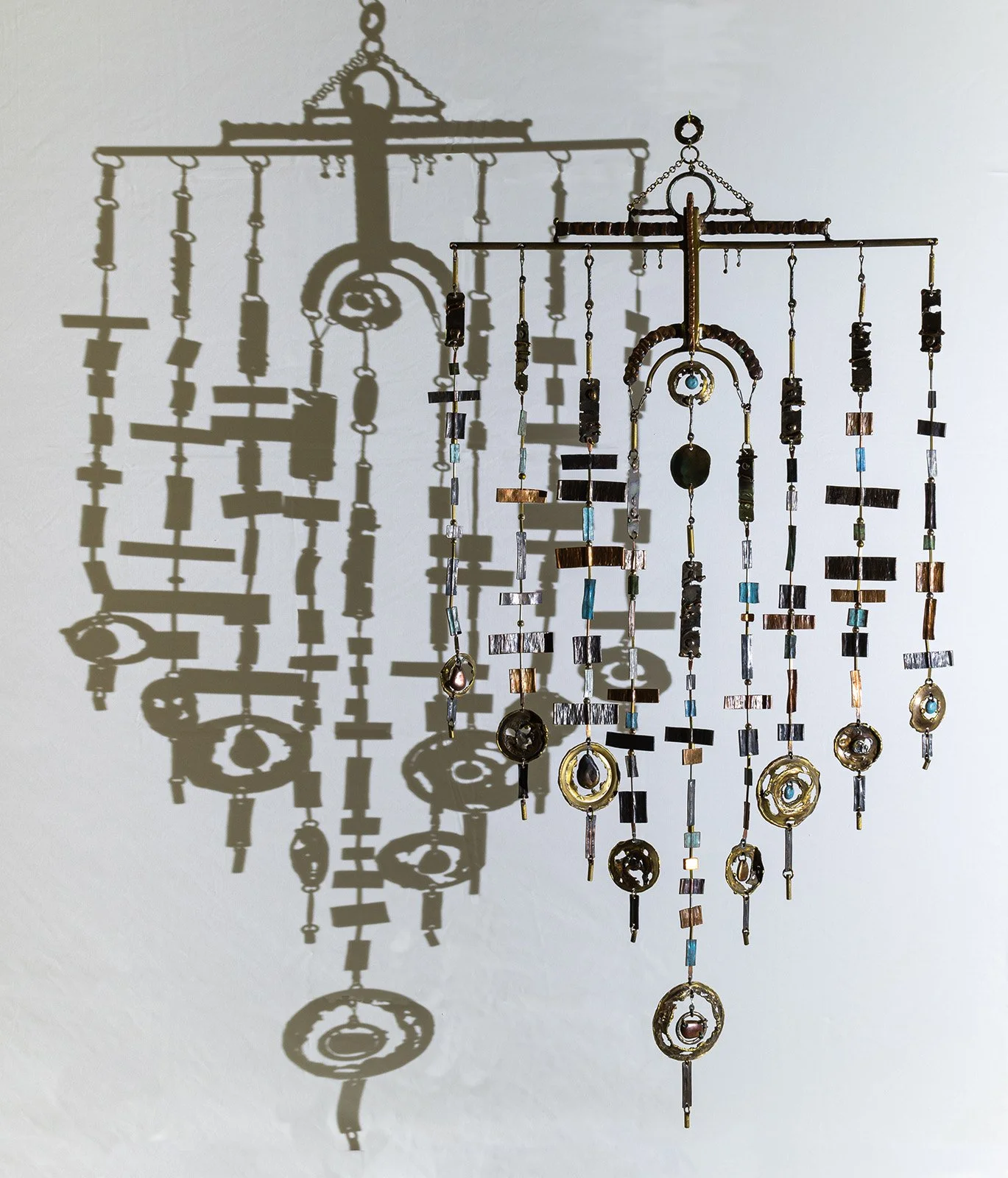 The cast shadow: a light drawing, made of everything the light did not touch. Nine threads on the wall, nine on the bar, the same count differently spaced.
