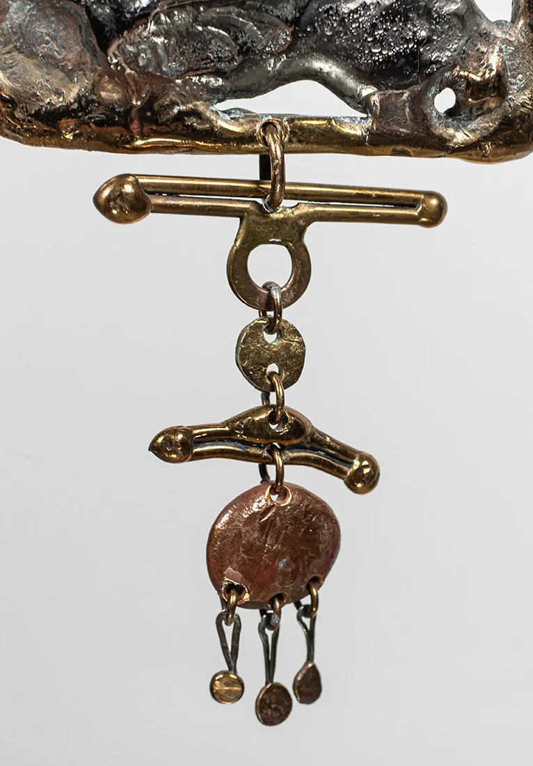The lower descent: a copper disc hung from a forged bar, with three small drops swinging free beneath it.