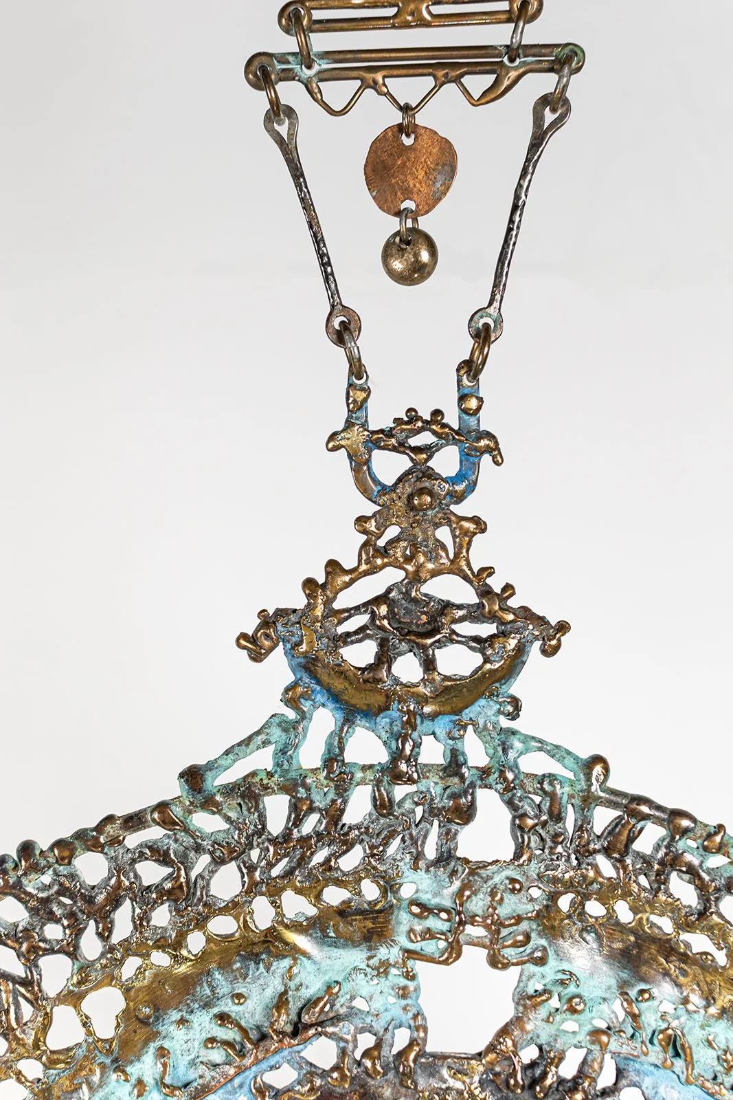 The crown above the ring, worked as ornamental lace in bronze, is the first thing the light meets and the first line the shadow draws.