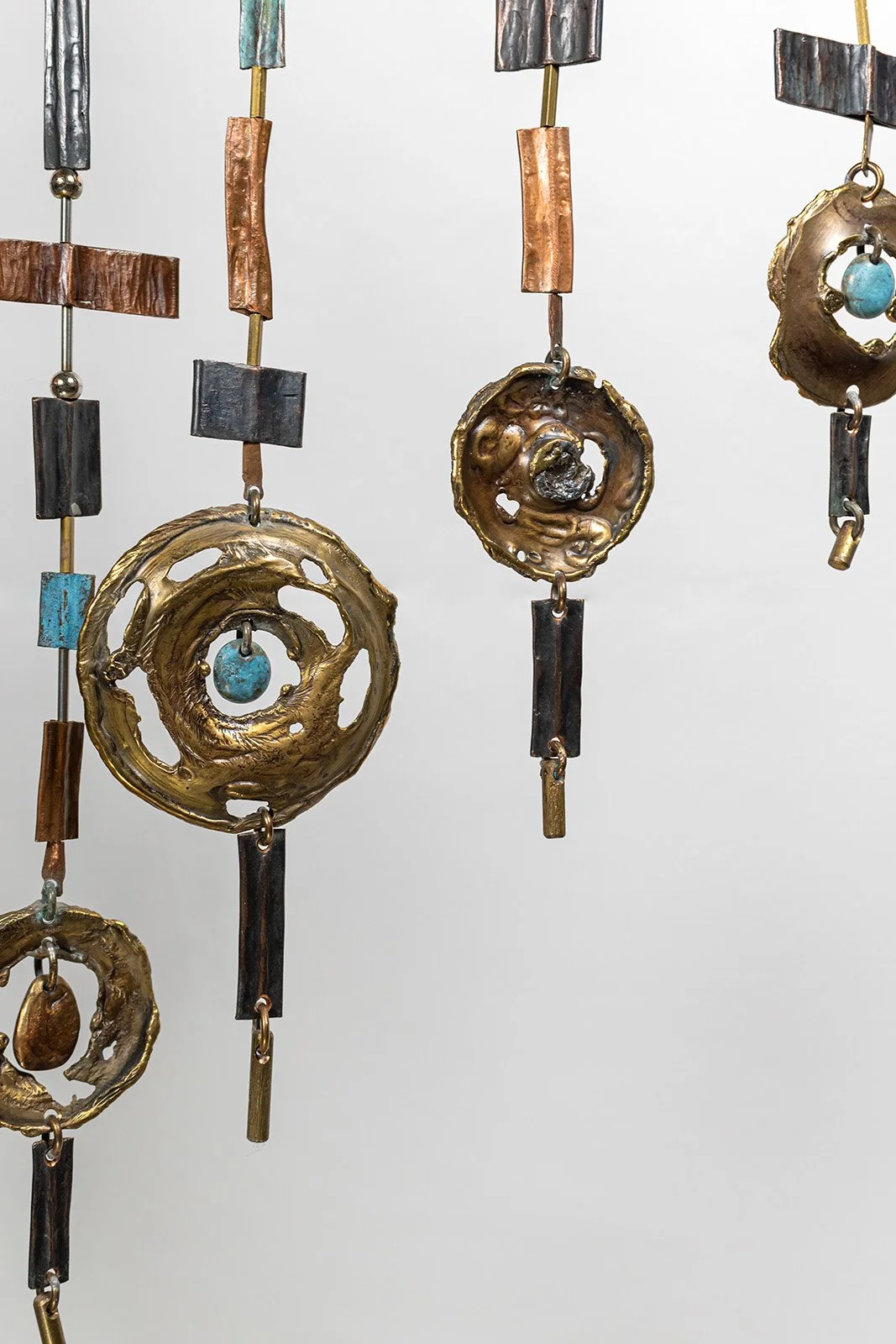 Every ring made by hand, scrolled and closed in flame, holding a  bronze drop like a stone the way a knot holds a thread.