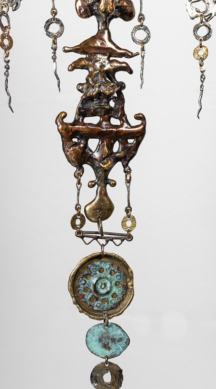 Weight answered by weight. Each drop hung to balance the one opposite it, the way a pectoral has always been balanced across a chest.