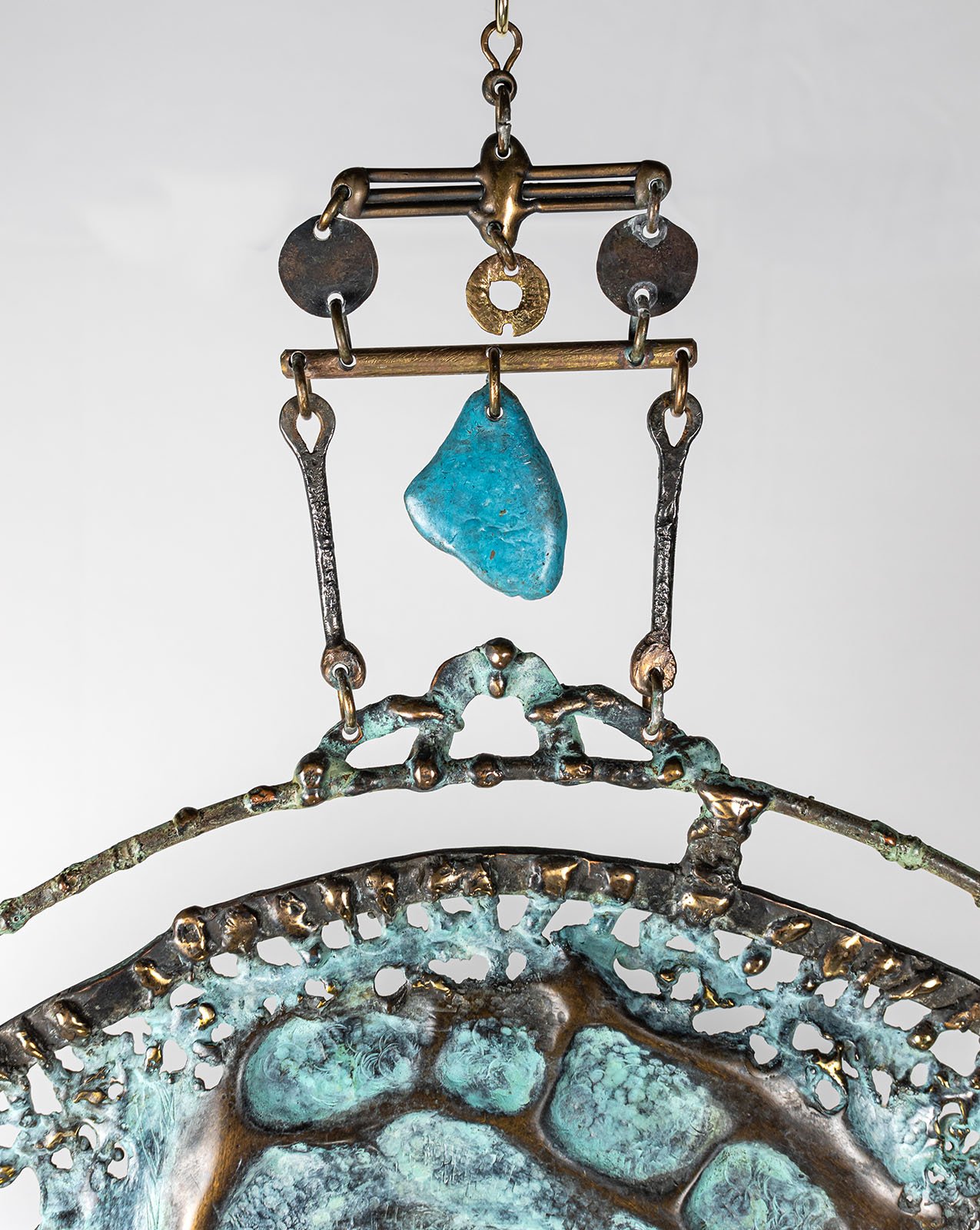 The crown above the ring, ornamental lace in bronze, set with a single turquoise drop.
