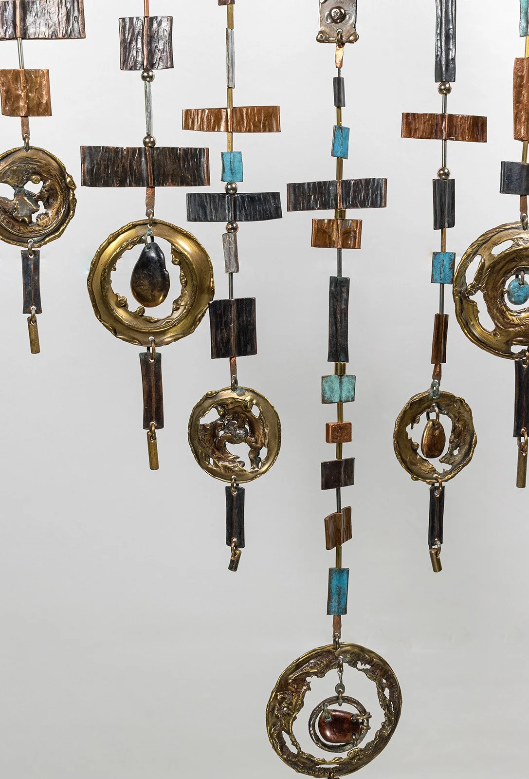 The vertical lines are the warp; the hammered copper and stainless steel crossing them are the weft, laid in by hand and flame.