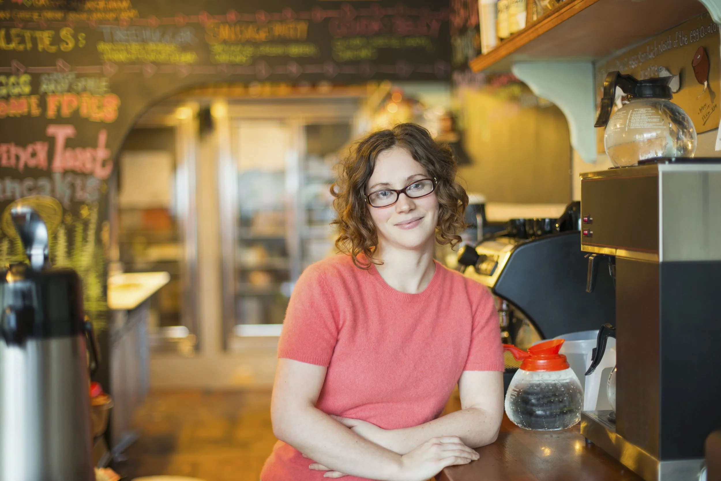 a-woman-leaning-on-a-cafe-counter-by-the-coffee-m-2026-03-25-00-33-43-utc.jpg