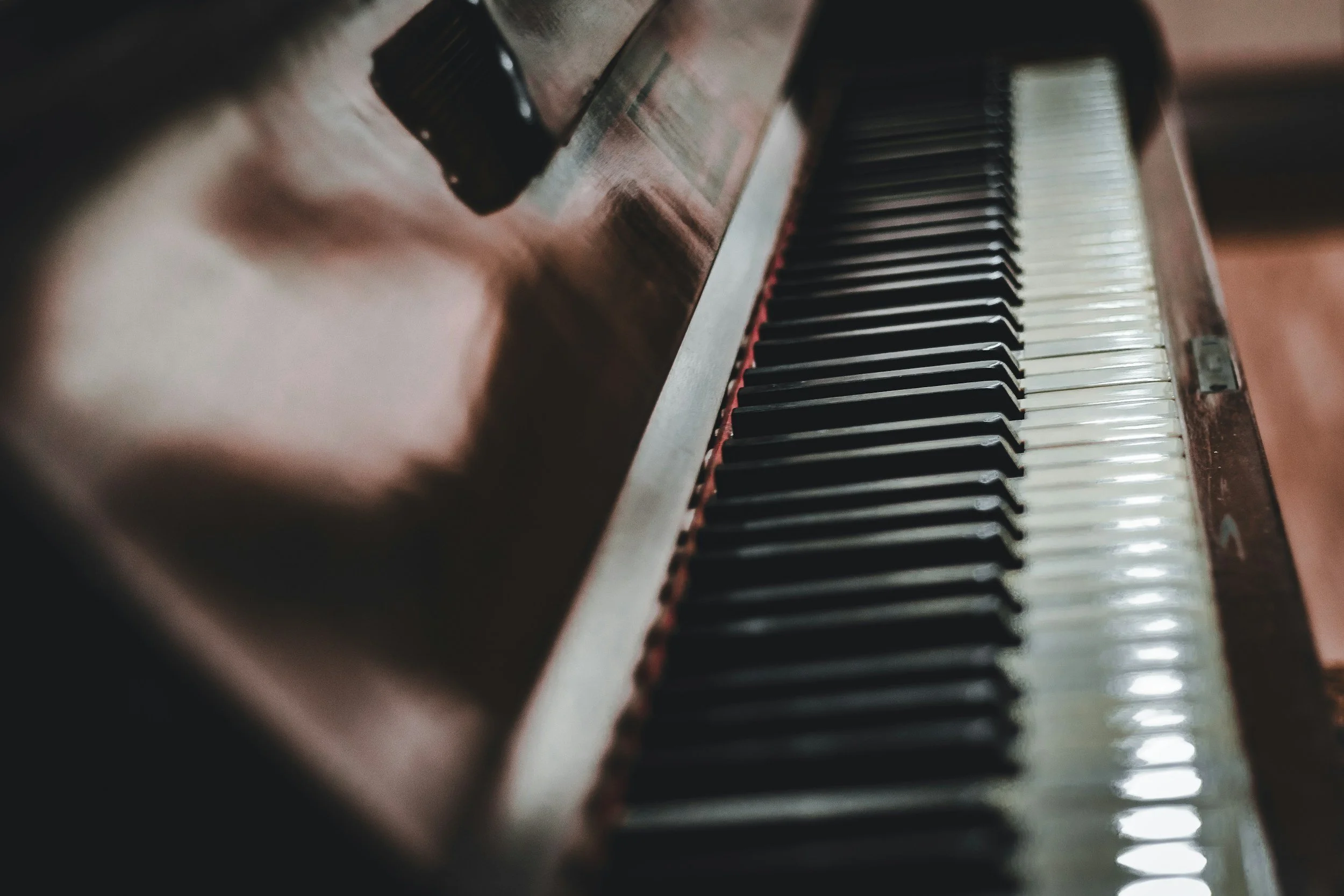 Close-up of a vintage piano keyboard showing black and white keys from an angle.