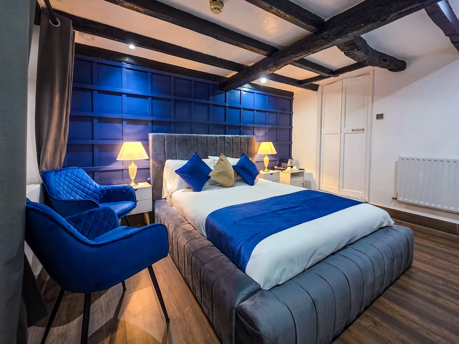 On-site double bedroom with blue upholstery and exposed beams