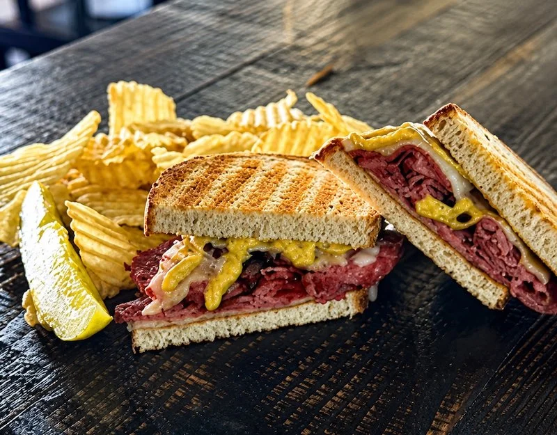 Toasted Pastrami Sandwich with chips and a pickle at Sam's in Chestertown