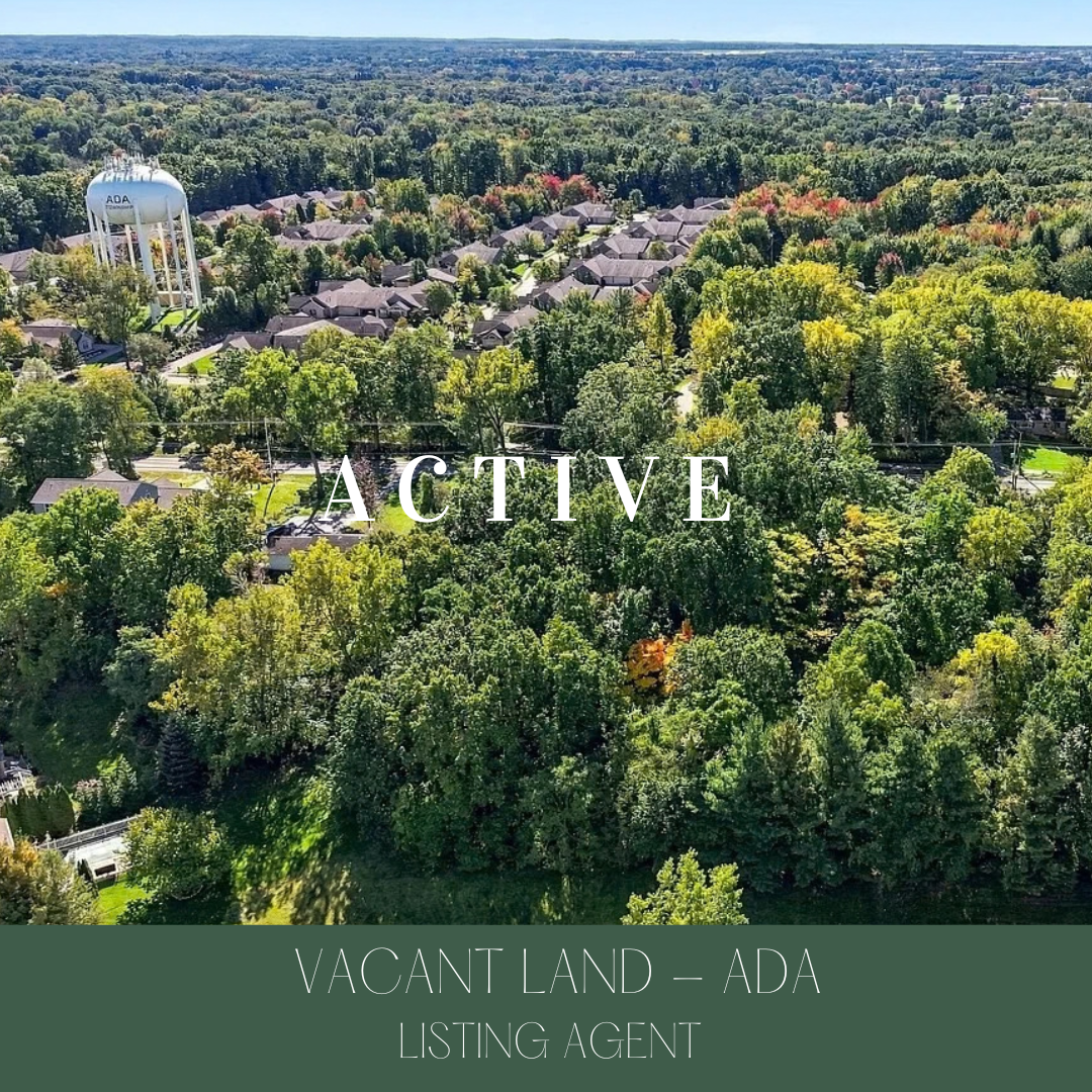 Aerial view of a suburban neighborhood surrounded by lush green trees and a water tower in the background.