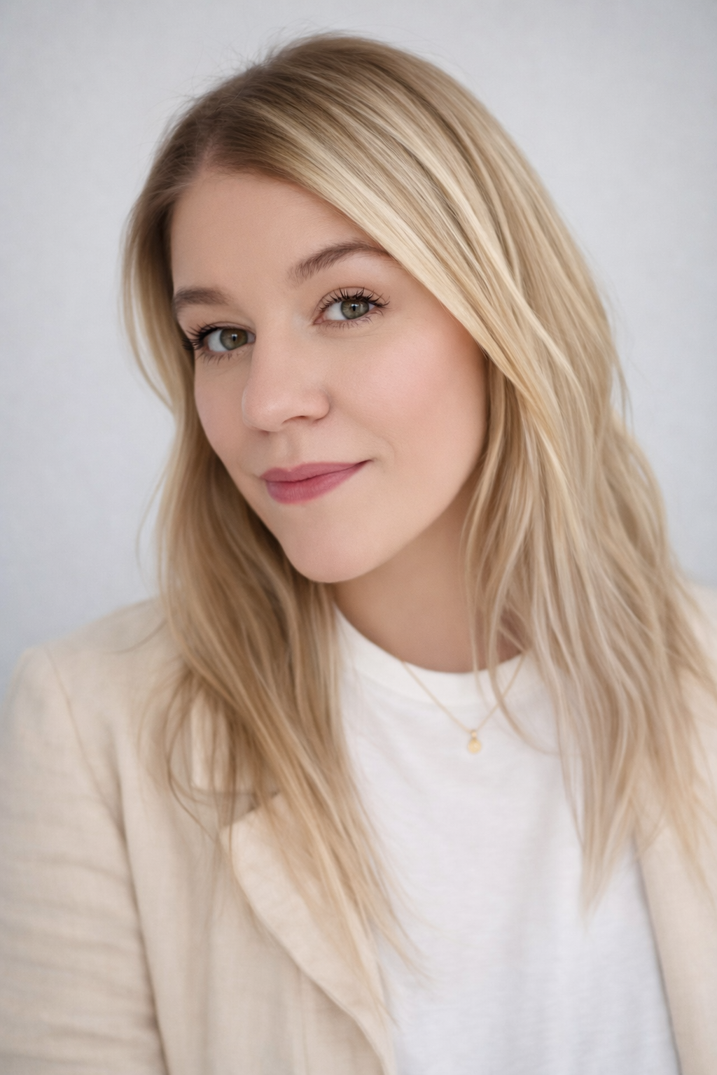 Close-up of a young woman with blonde hair, light makeup, and a slight smile, wearing a white top and a beige blazer. Heather Smith is a West Michigan Realtor with 616 Realty.