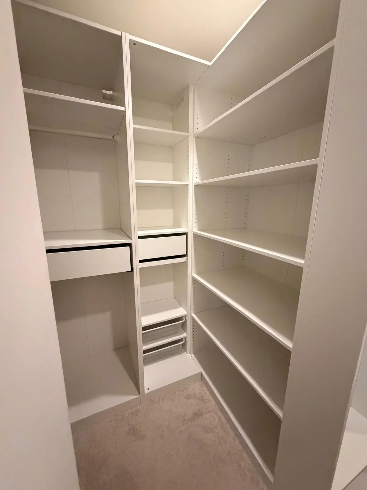 Empty white closet with shelves, drawers, and compartments.