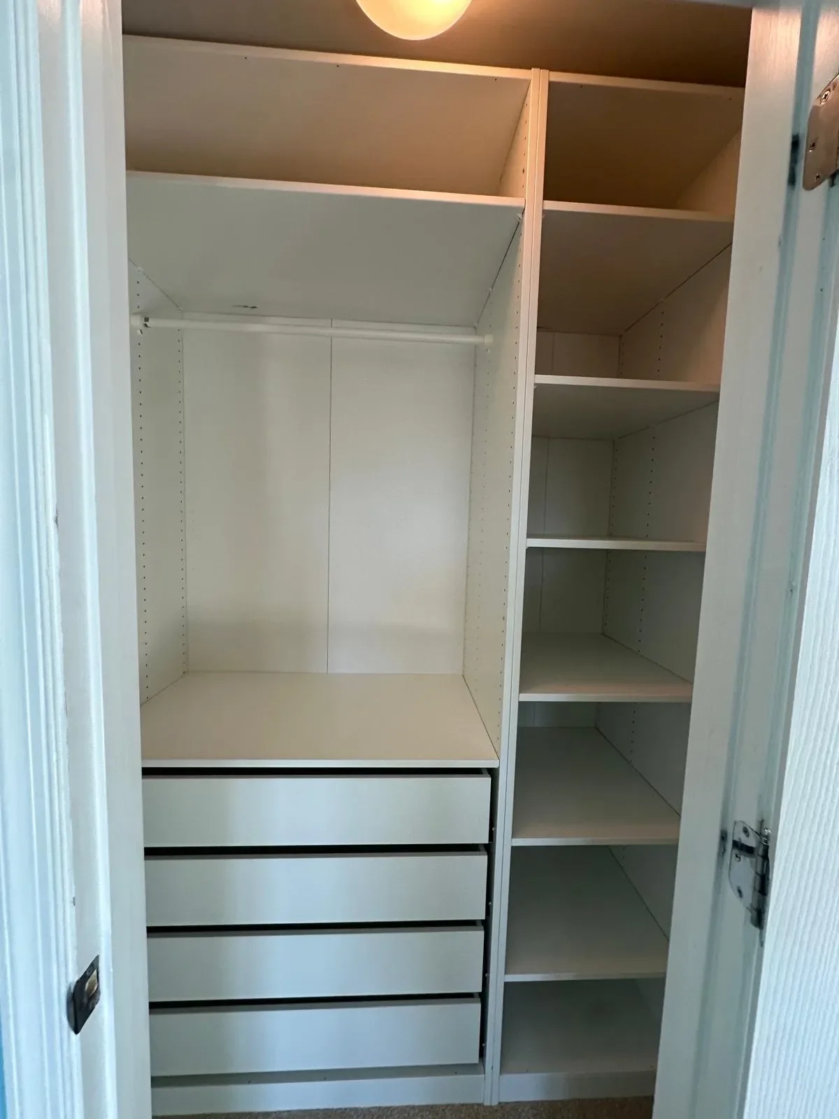 Empty white closet with shelves and drawers, open door revealing organized storage space.
