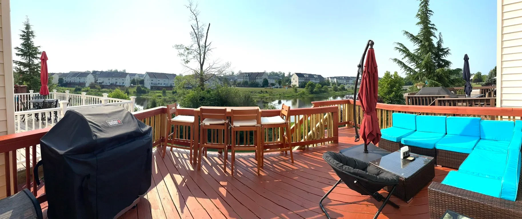 Deck with outdoor furniture, including blue cushioned sectional sofa, black coffee table with a 