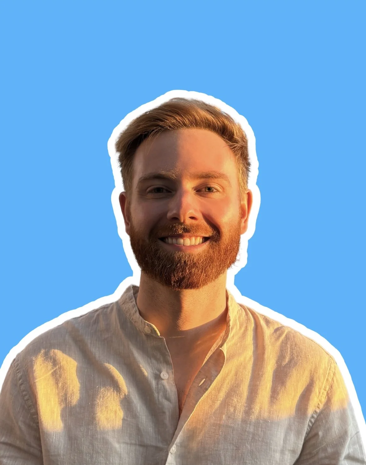 Portrait of a smiling man with a beard and short hair, wearing a light-colored shirt, outlined with a white border against a clear blue background