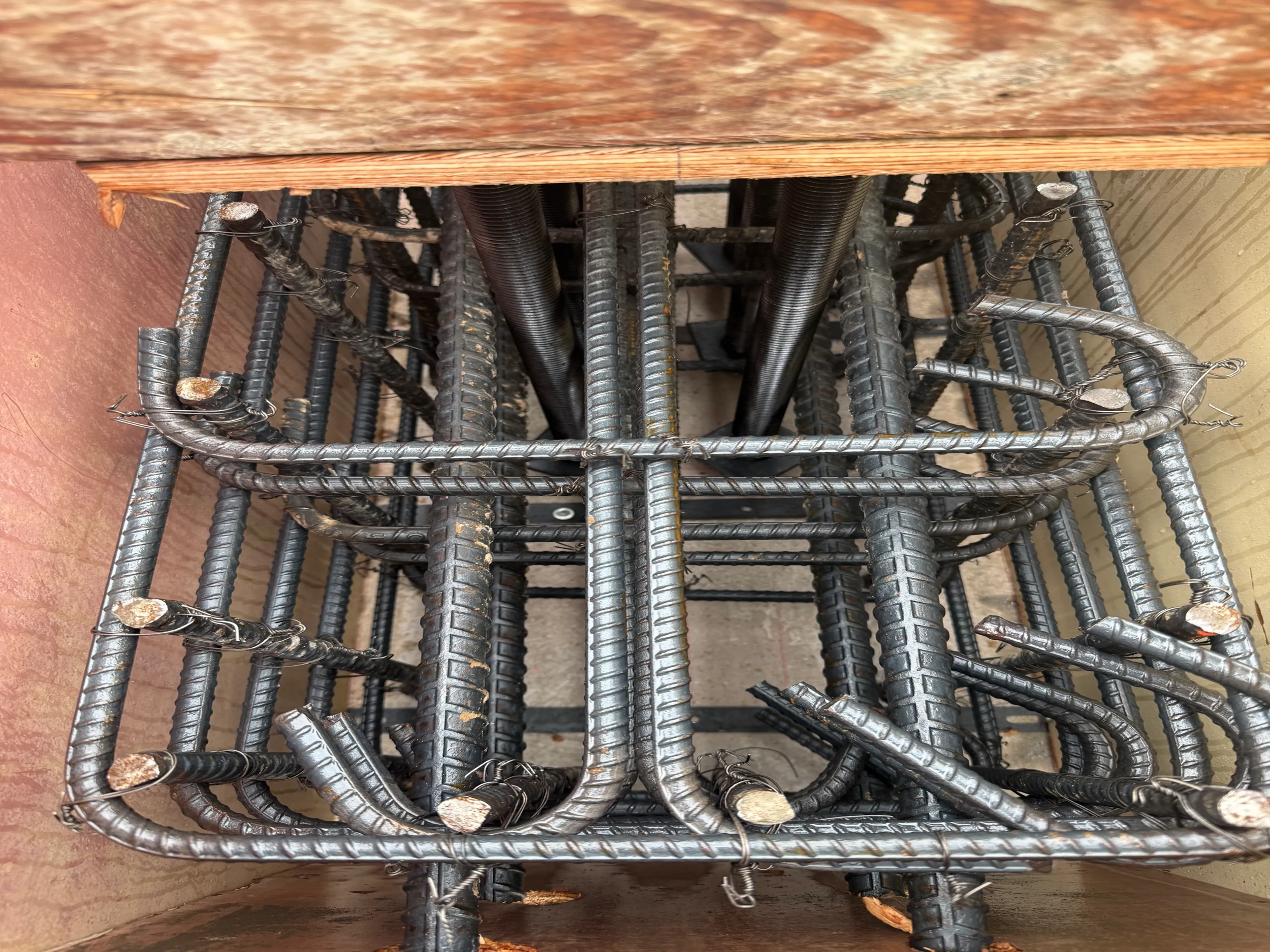 Metal rebar structures stacked inside a cardboard box, used for concrete reinforcement.