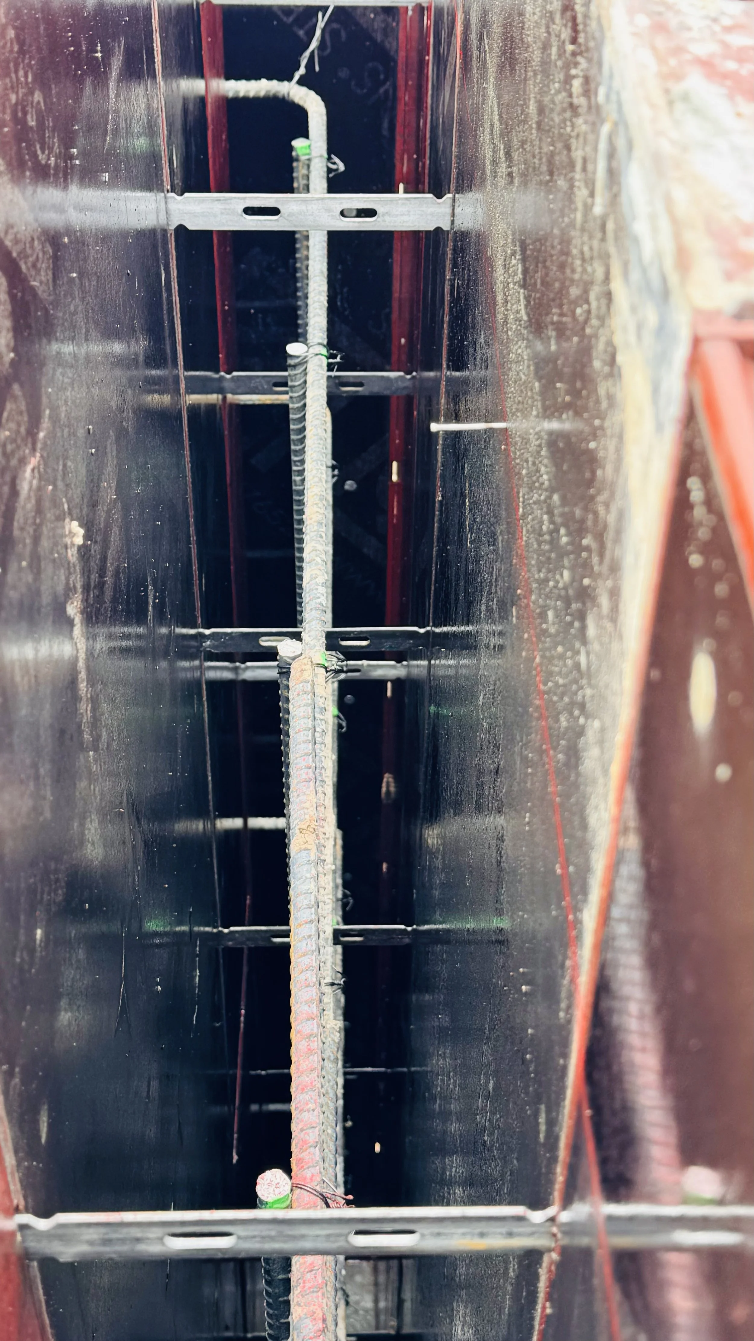 Inside a vertical shaft with a central rebar and metal supports.