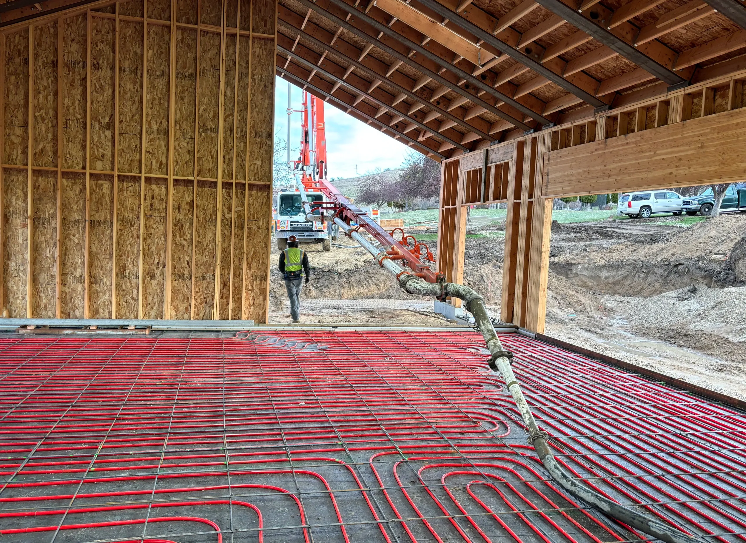 Construction site with rebar and concrete pumping equipment for pouring a floor inside a building under construction.