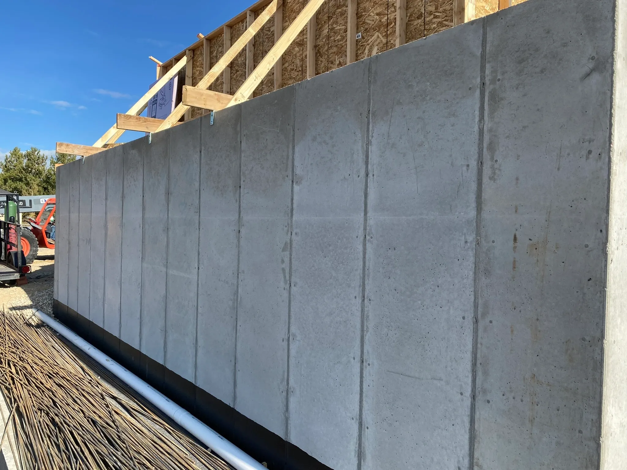 Concrete wall under construction with wooden framing and blue sky in the background.