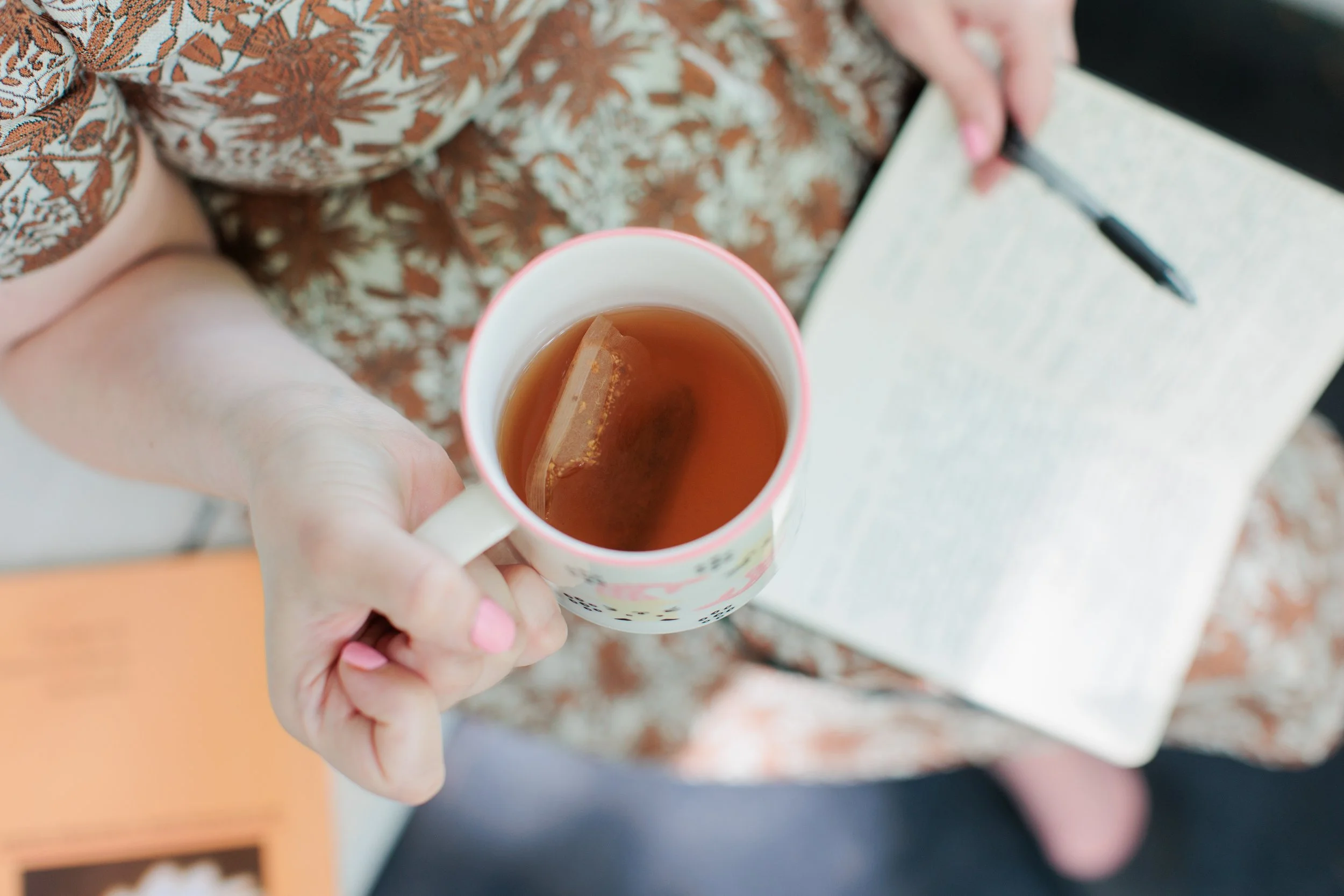 Chelsea Turner LCSW-C, is pictured holding tea and a journal, creating a calm and welcoming space for therapy, self-understanding, and healing.