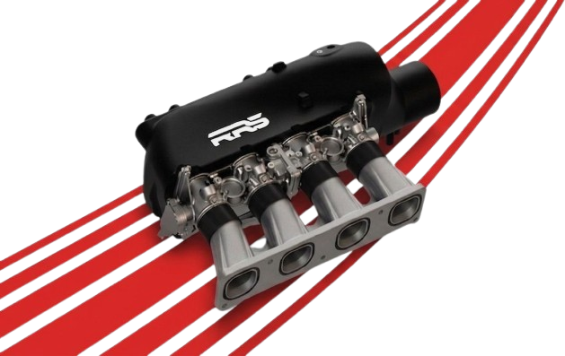 A car engine intake manifold with a black cover and four silver intake runners, placed on a surface with red and teal stripes.