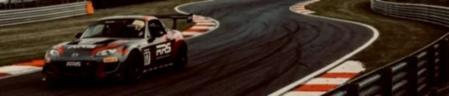 A race car driving on a curved race track during daytime.