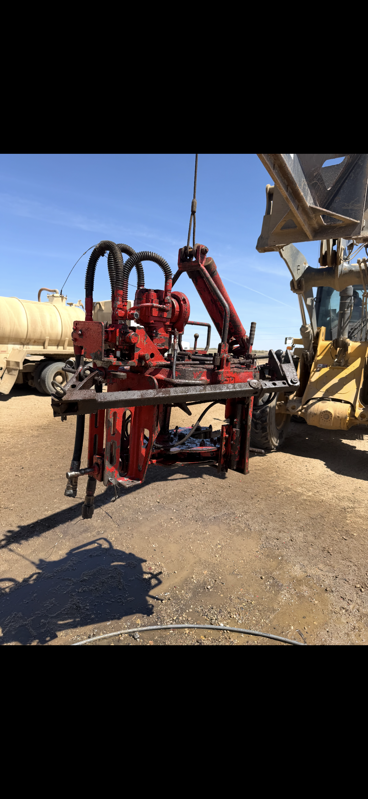 Construction equipment and machinery on a dirt lot, with a clear blue sky in the background.