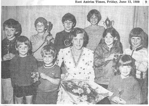 Group of children and a woman posing for a photo, some children holding trophies and flowers, in black and white, from a newspaper clipping dated June 13, 1980.