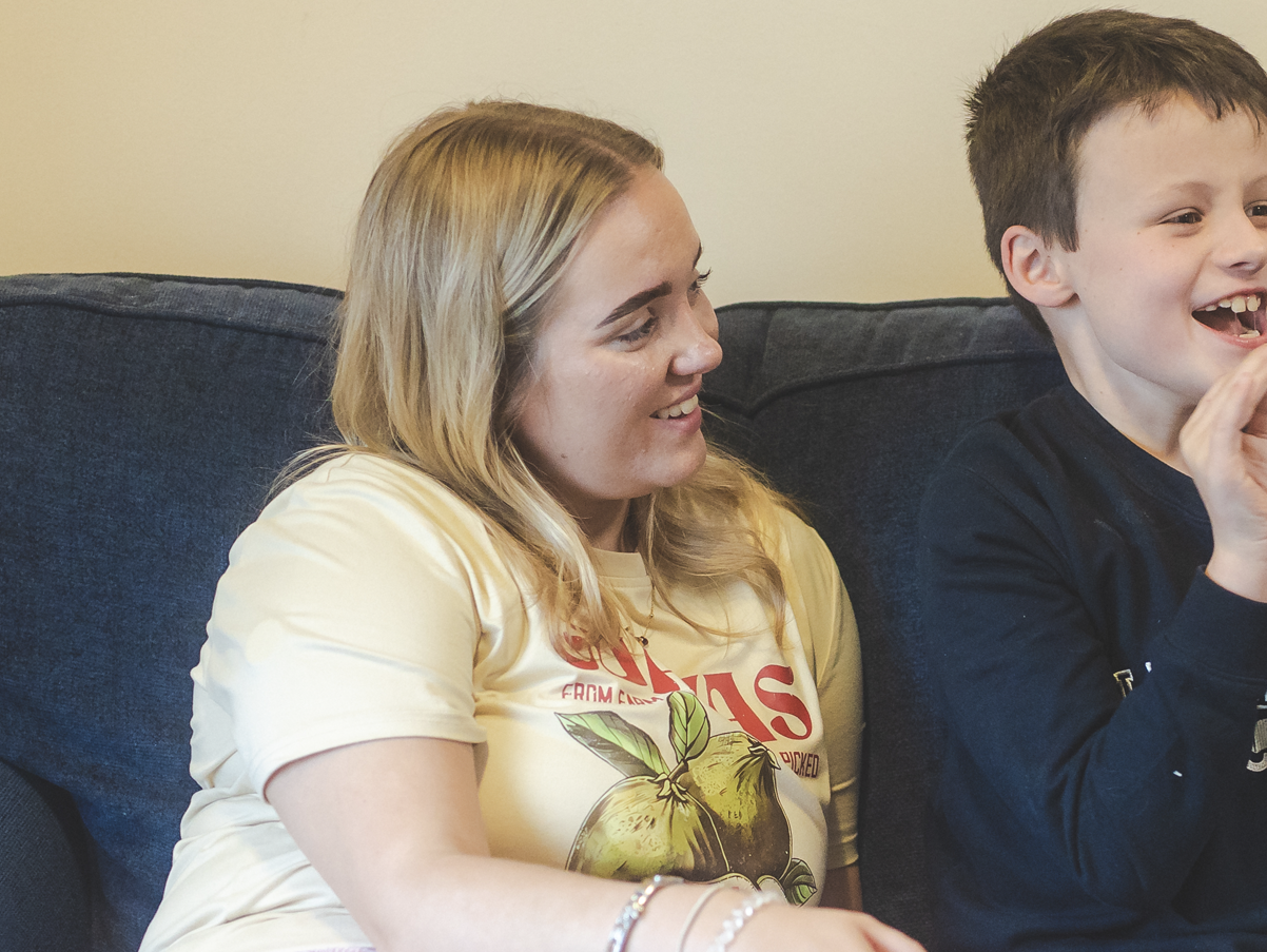 A woman and a boy sitting on a dark blue couch, smiling and having a good time.