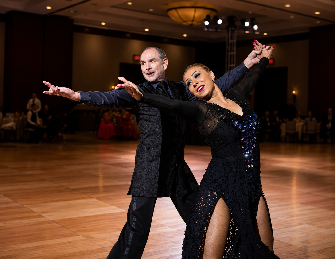 Professional ballroom dance couple performing in elegant dancewear.