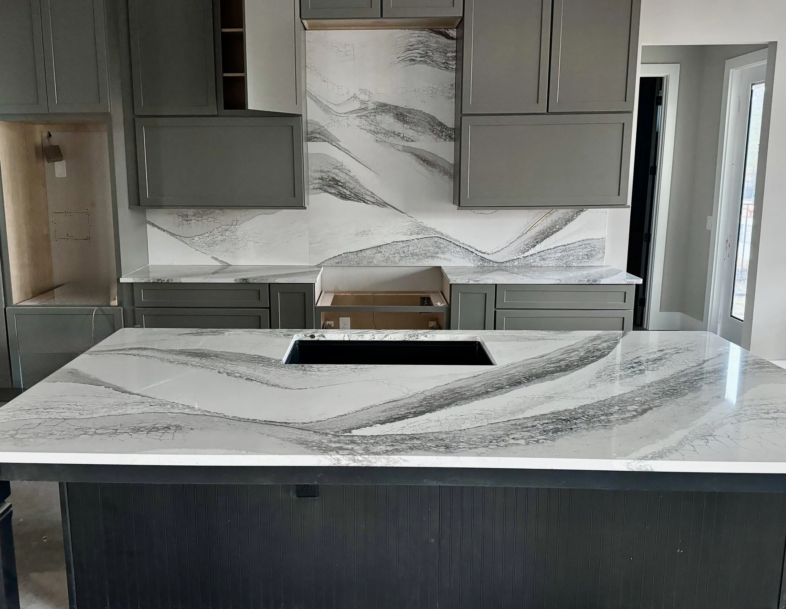 Modern kitchen with gray cabinets and a marble island with gray and white veining.