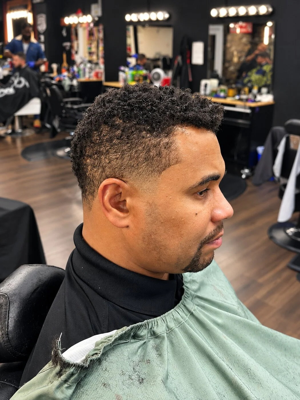 Right-side view of a textured curl cut, taper, and beard detail at Prime Time Barber Lounge.