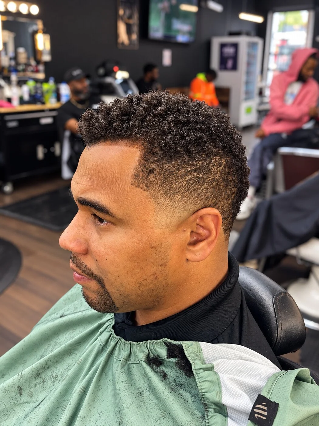 Textured curly haircut with a sharp line-up and taper at Prime Time Barber Lounge in Silver Spring.