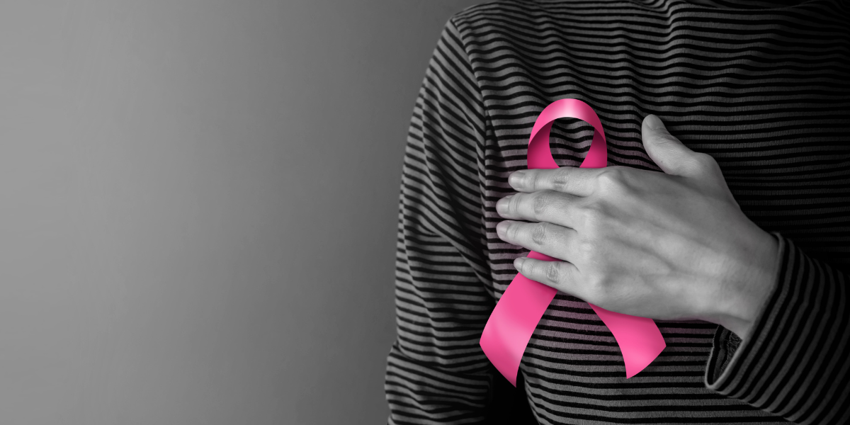 Une personne en chemise rayée noire et blanche avec un ruban rose, symbole de la lutte contre le cancer du sein, sur la poitrine.