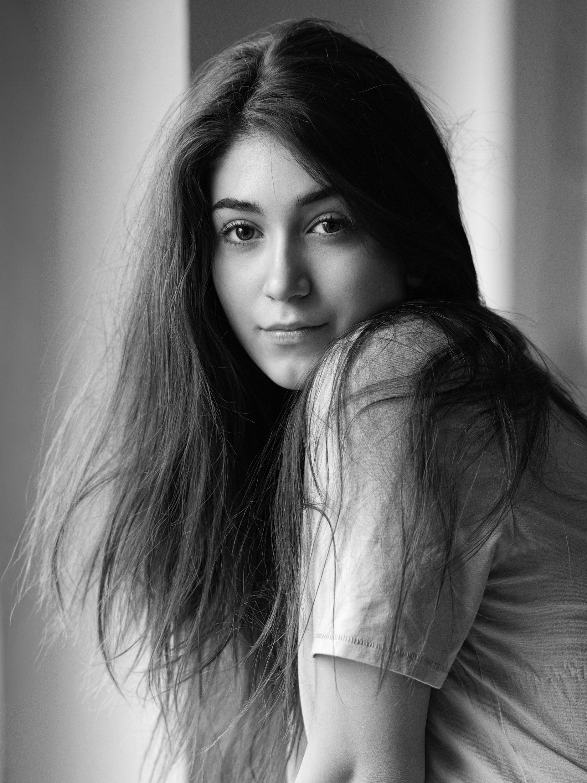 Alicia, black and white portrait looking over shoulder with soft gaze, long dark hair, natural light, Hamburg