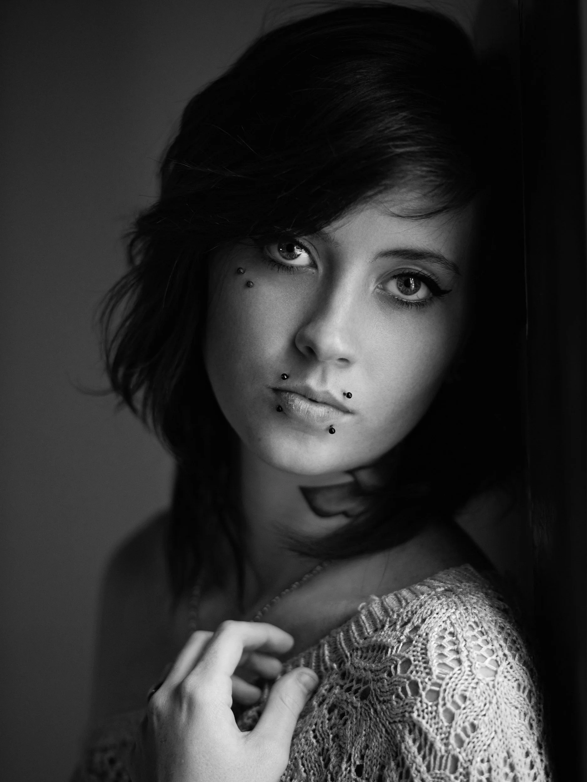 Effy, close-up black and white portrait with moody gaze, facial piercings, dark hair, hand to chest, Atlanta studio