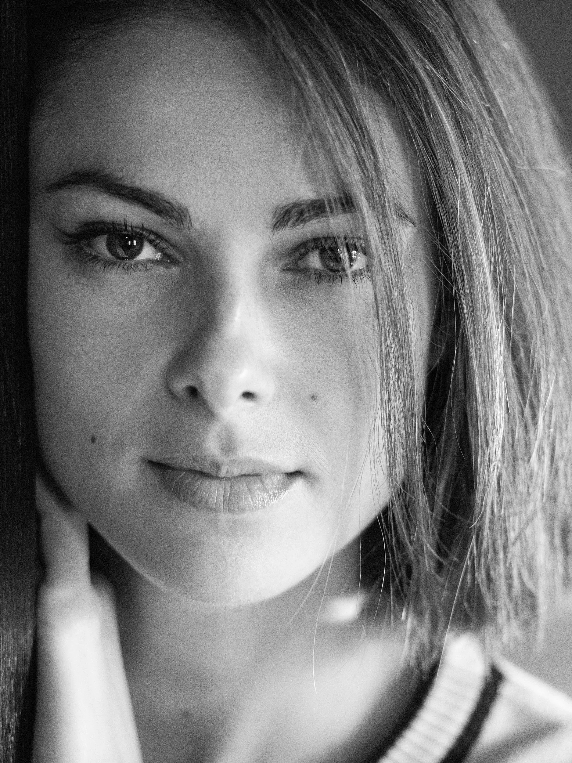 Atanaska, close-up black and white portrait with intense gaze, natural light, hand to jaw, wooden frame, Atlanta
