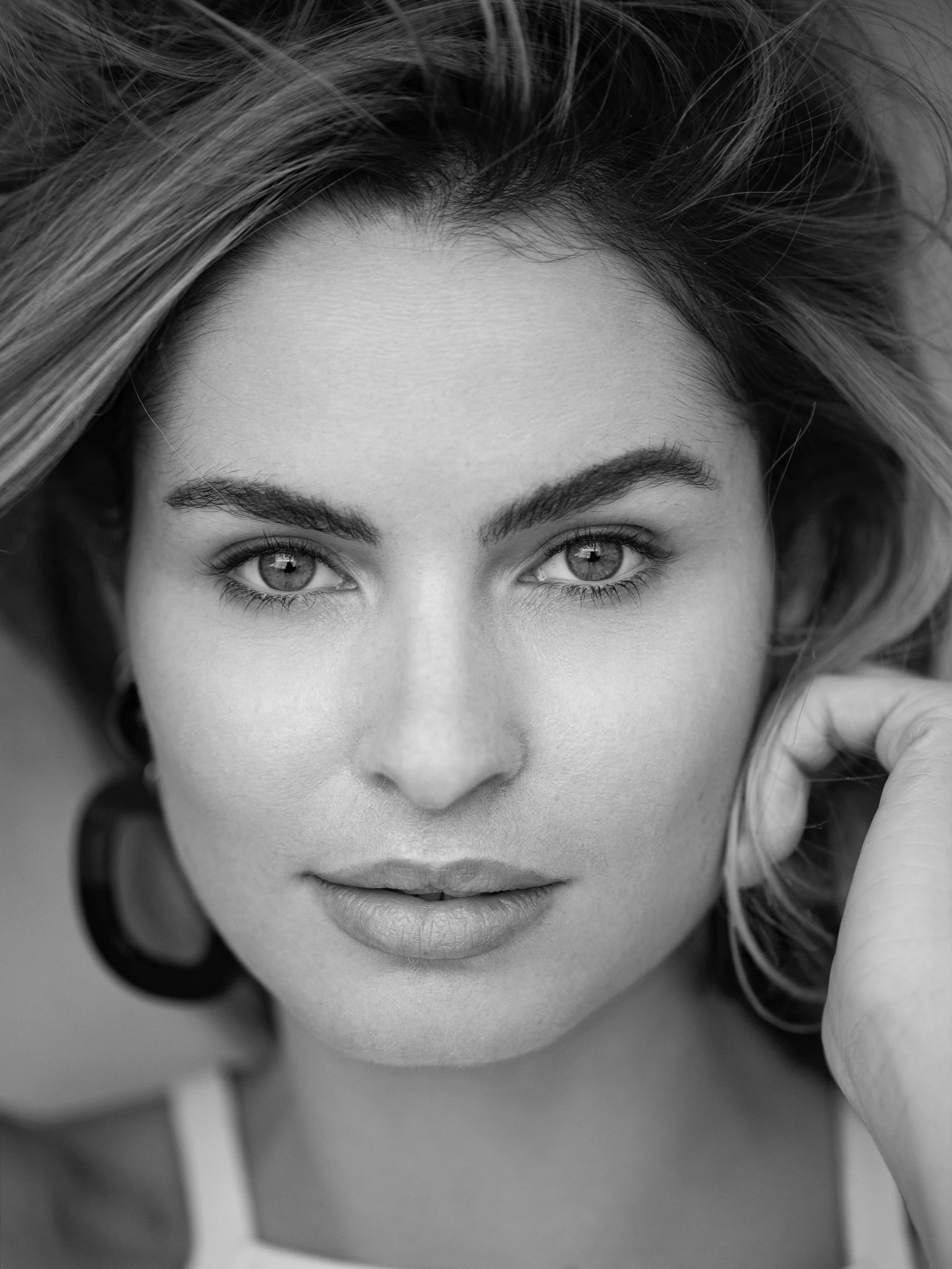 Severine, close-up black and white portrait with direct frontal gaze, strong brows, windswept hair, studio