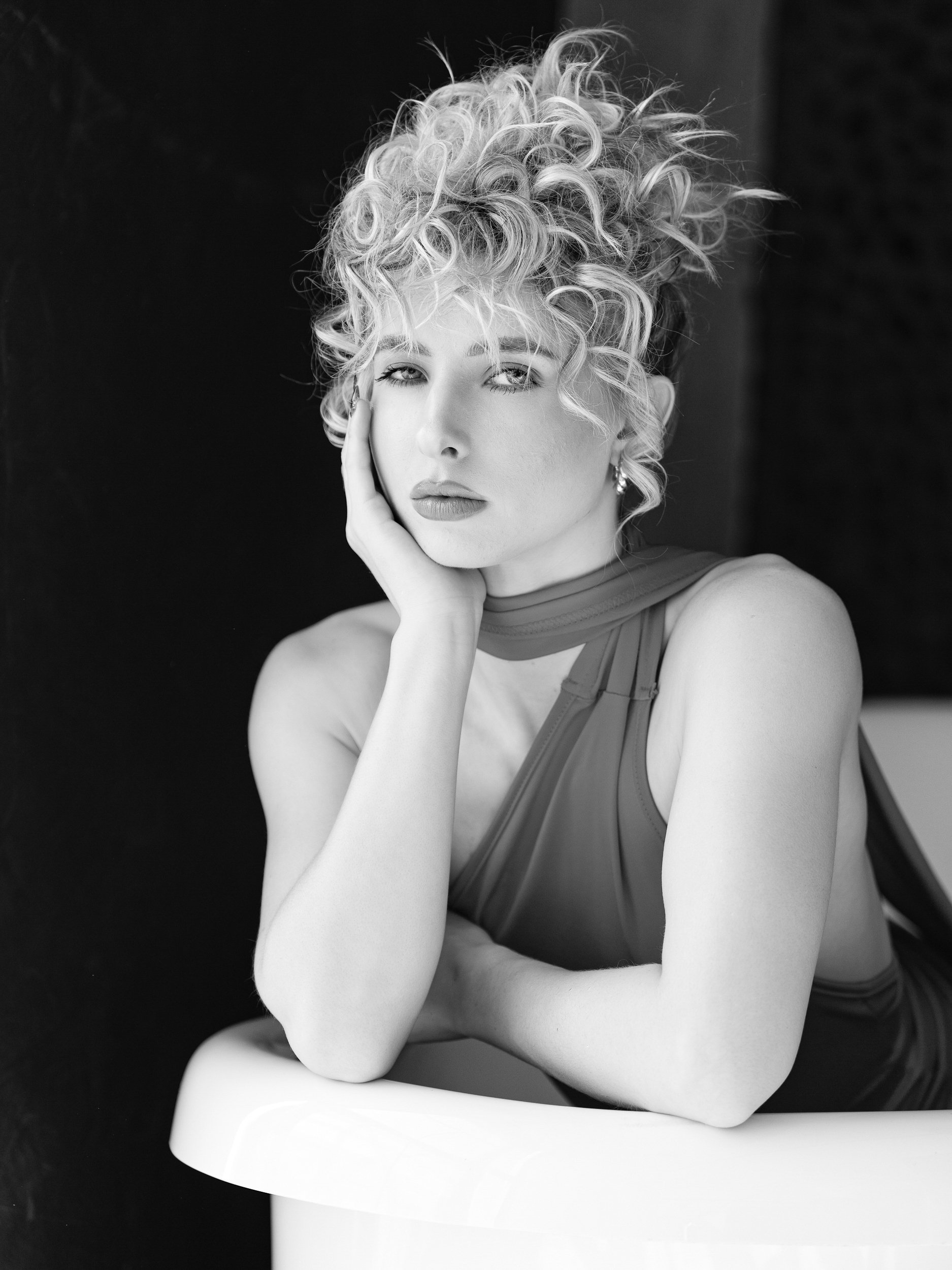 Savannah, black and white portrait leaning on bathtub edge, contemplative gaze, wild curly updo, dark studio background