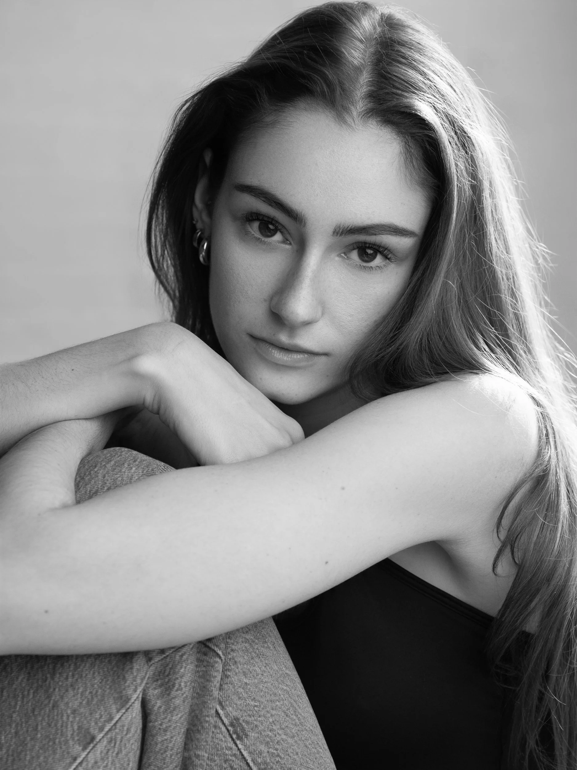 Monica, close-up black and white portrait with direct contemplative gaze, arms crossed, bare shoulders, studio