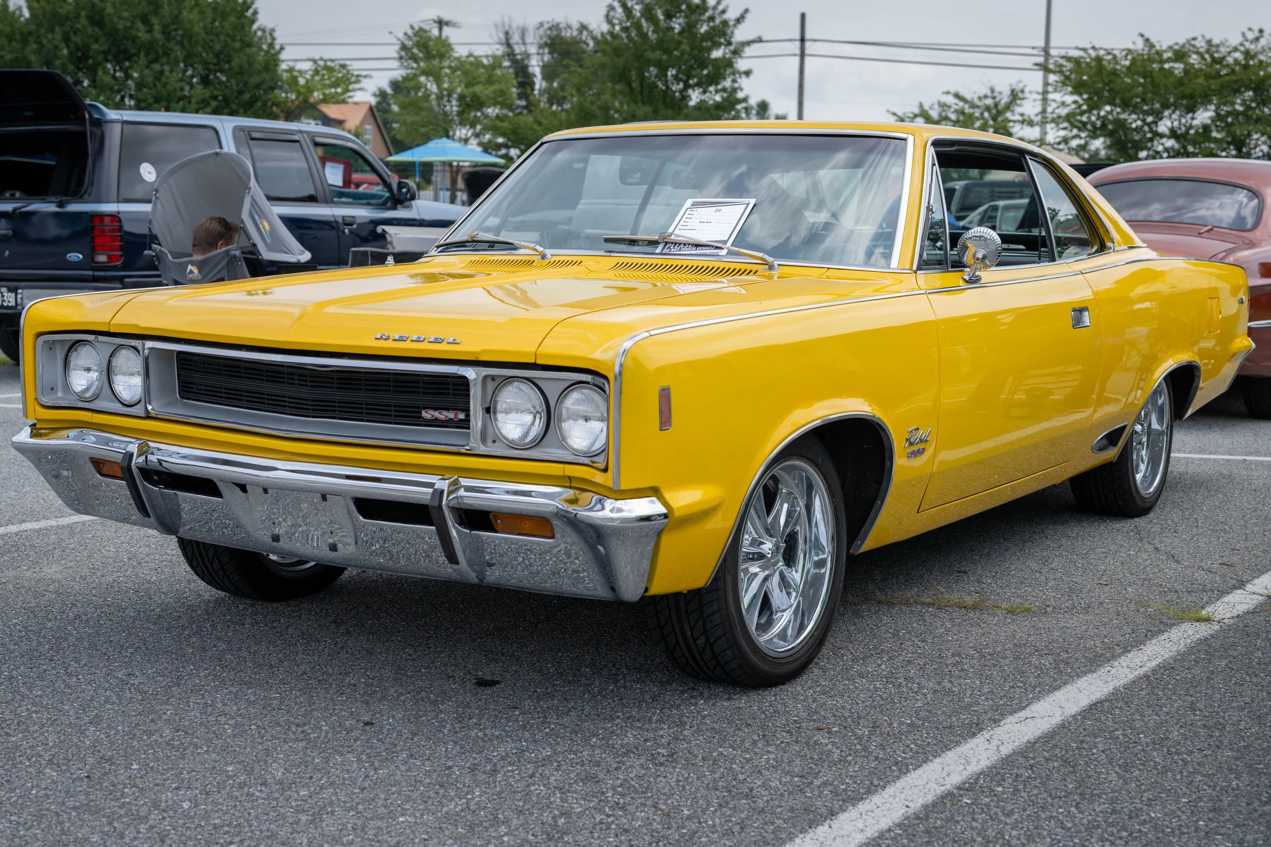 Yellow vintage classic muscle car parked at an outdoor car show.